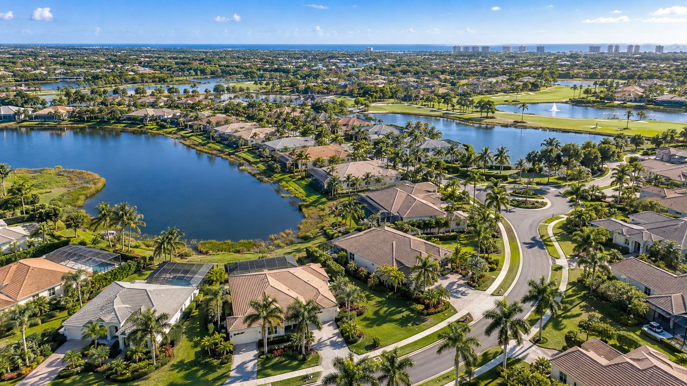 Aerial style lifestyle image of a lakefront Naples community with tile roof homes, palms and the Gulf on the horizon, inspired by Valencia Sky