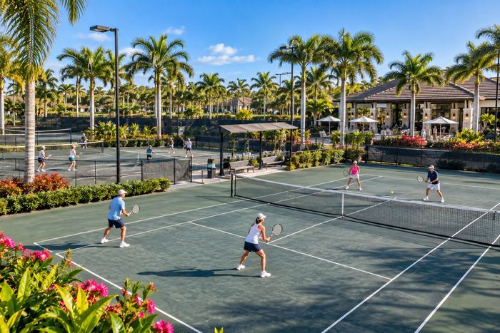 Illustrative lifestyle image of lighted clay tennis courts with shaded seating